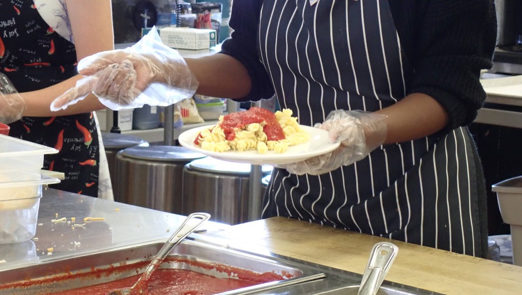 Kitchen staff serving a plate of pasta.